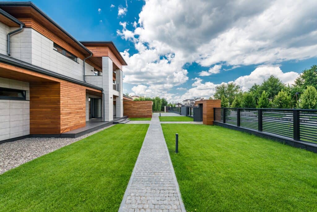 Yard of contemporary house with trees outside fence