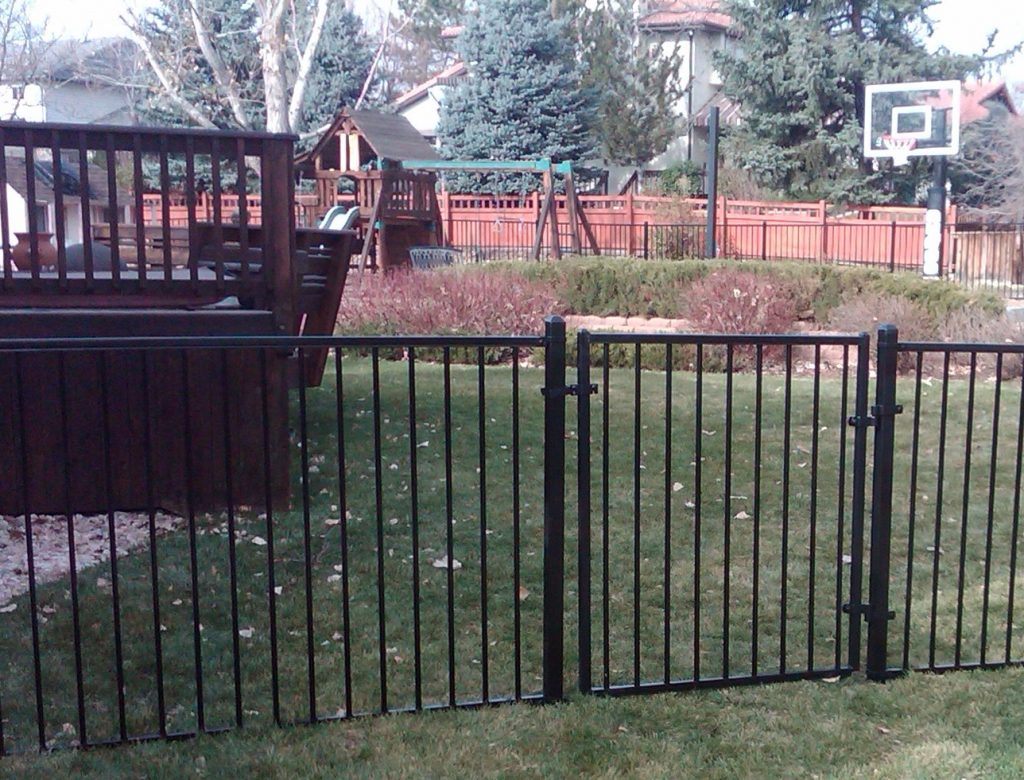 A grass basketball court enclosed in wrought iron fence